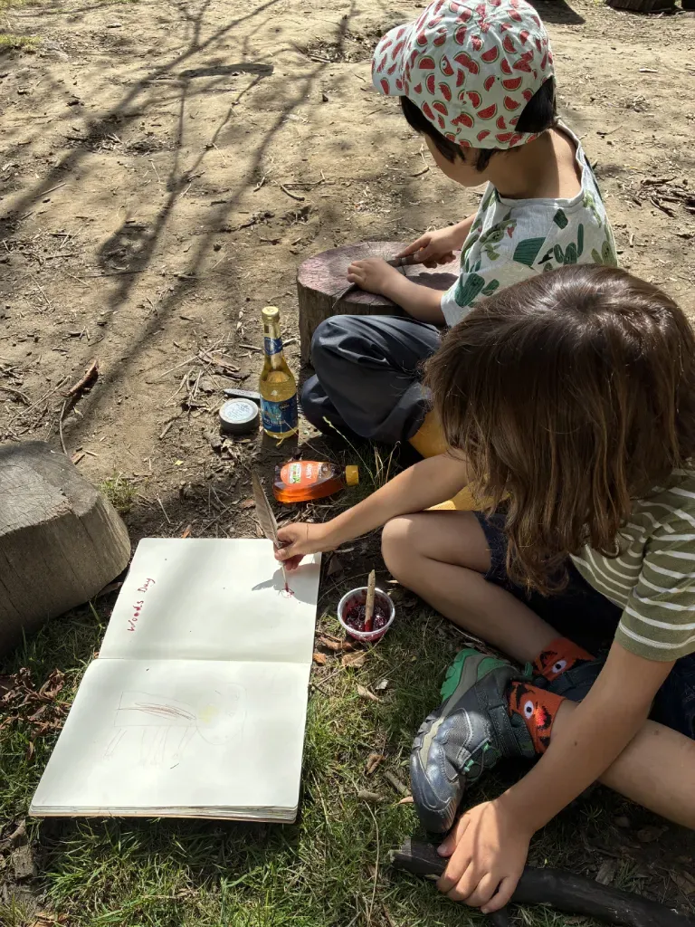A child crouched low, carefully placing found natural objects on a wooden ledge