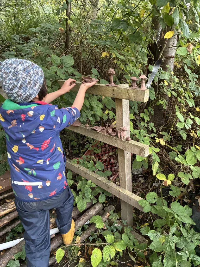 Small clay figures — mushrooms and woodland creatures — drying on a wooden rail