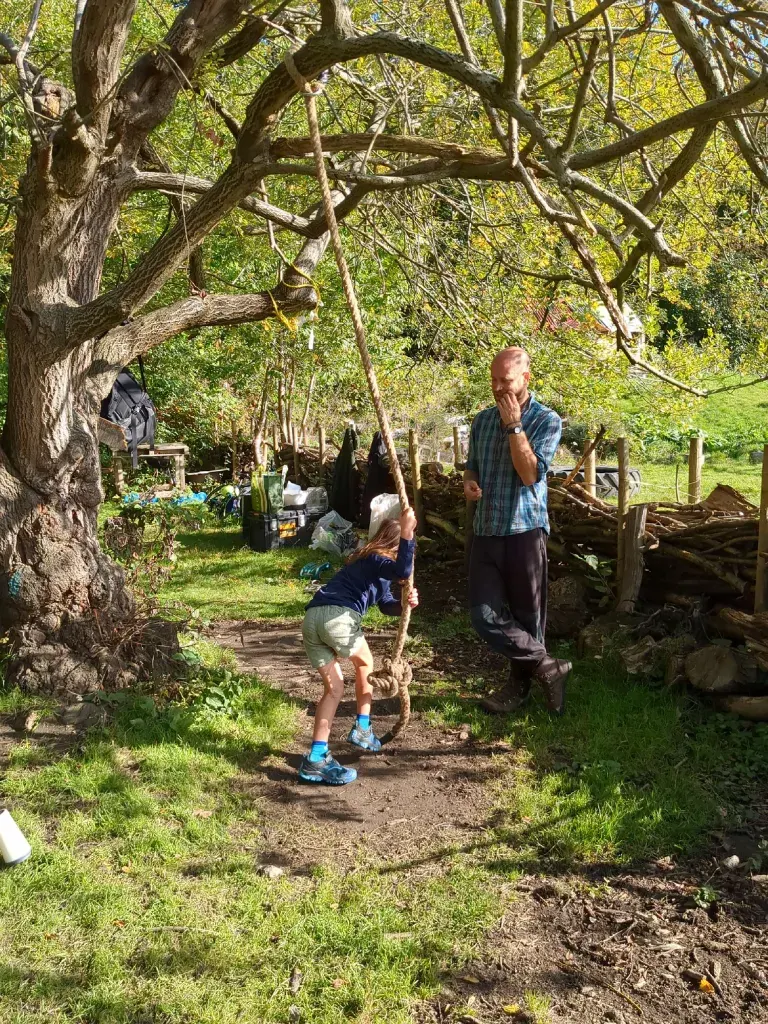 A child mid-air on a rope swing beneath a large tree