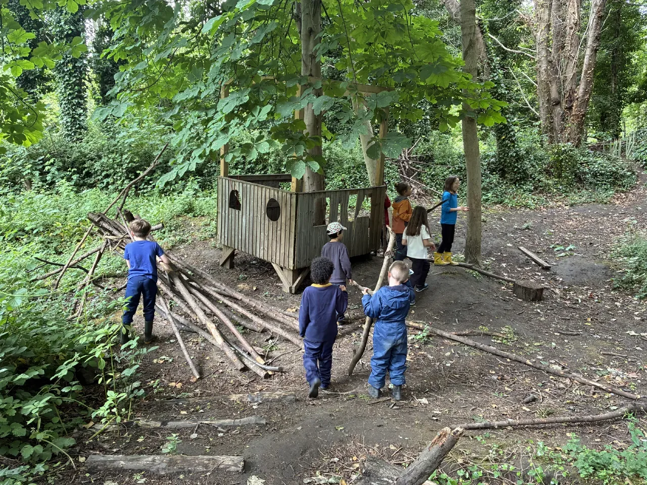 Children stacking logs together as part of den-building
